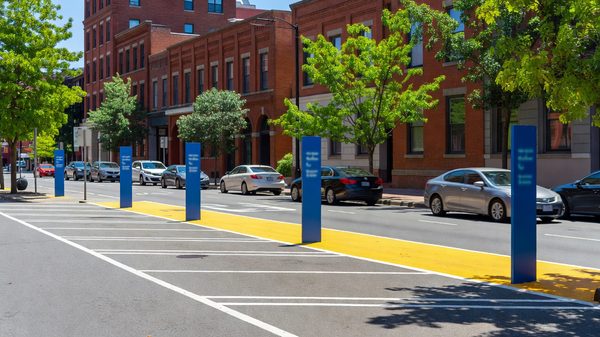Busy city street with marked kerbside parking bays, loading zone and passing traffic